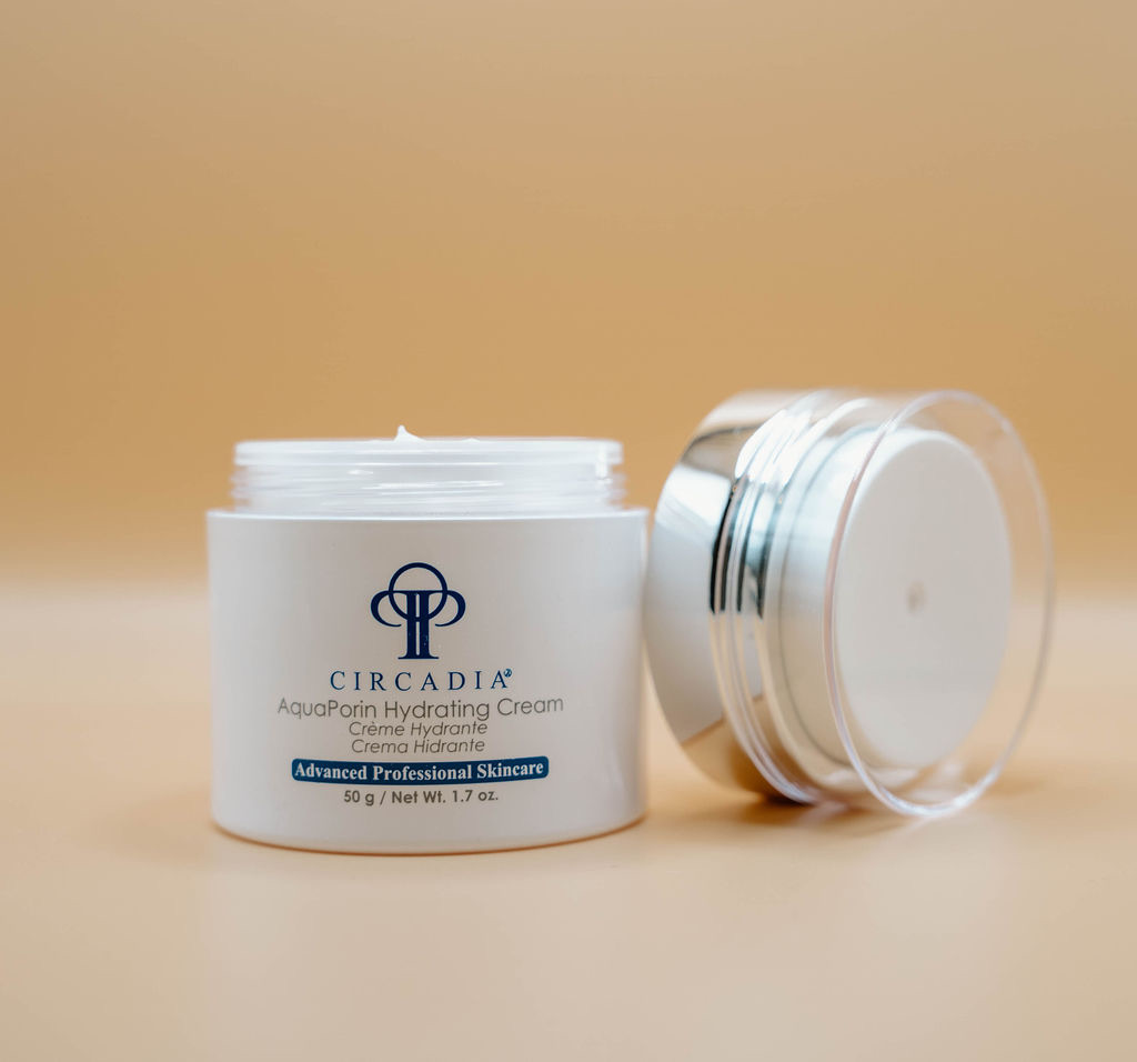 An open jar of Circadia AquaPorin Hydrating Cream is displayed with its lid placed beside it against a beige background. The jar contains 50g (1.7 oz) of product.